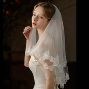 Pearl lace hair comb attached to a mid-length chiffon wedding veil