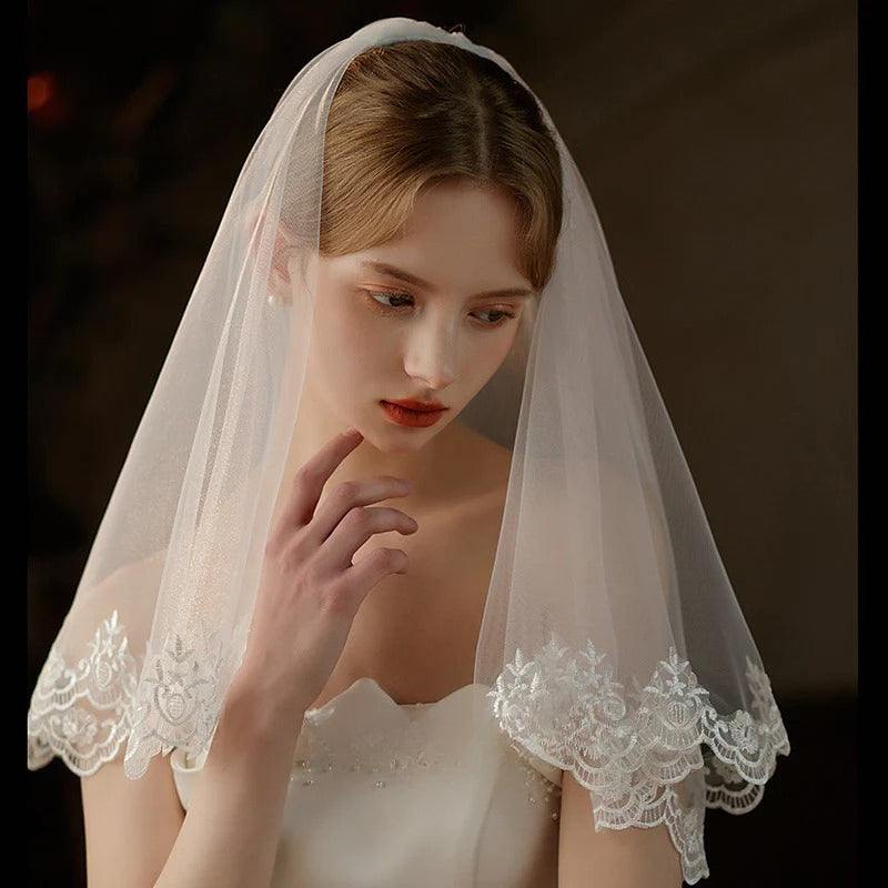 Pearl lace hair comb attached to mid-length sheer bridal veil for wedding ceremonies