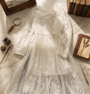 Young girl wearing a long white lace fairy dress with delicate floral lace and flowing skirt for special occasions