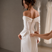 Ivory off-shoulder satin mermaid wedding guest dress with pearl draped detailing and long sleeves