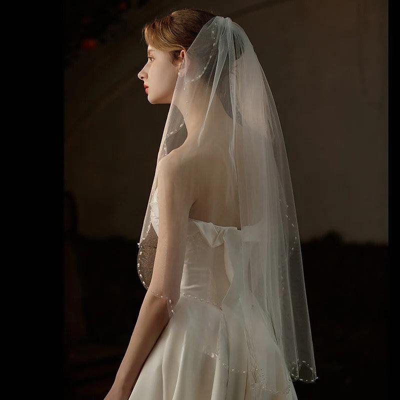 Soft mid-length lace trim bridal veil with comb, made of sheer chiffon tulle for elegant wedding look