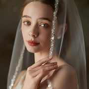 Handmade beaded metal comb securing a mid-length soft chiffon bridal veil