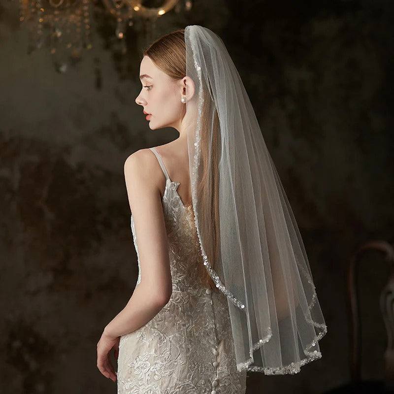 Handmade beaded metal comb holding a mid-length soft chiffon bridal veil